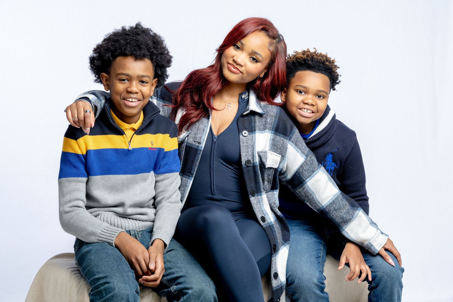 A happy family wearing coordinated blue and grey outfits poses together on a white background.