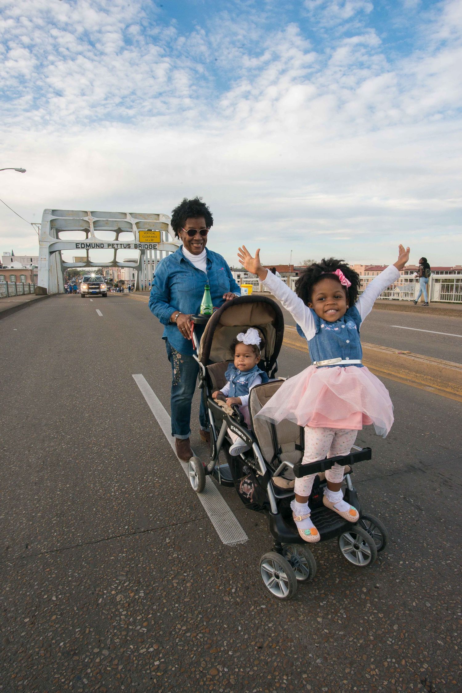 Family enjoying a stroll with a baby stroller on a sunny day with blue skies overhead.