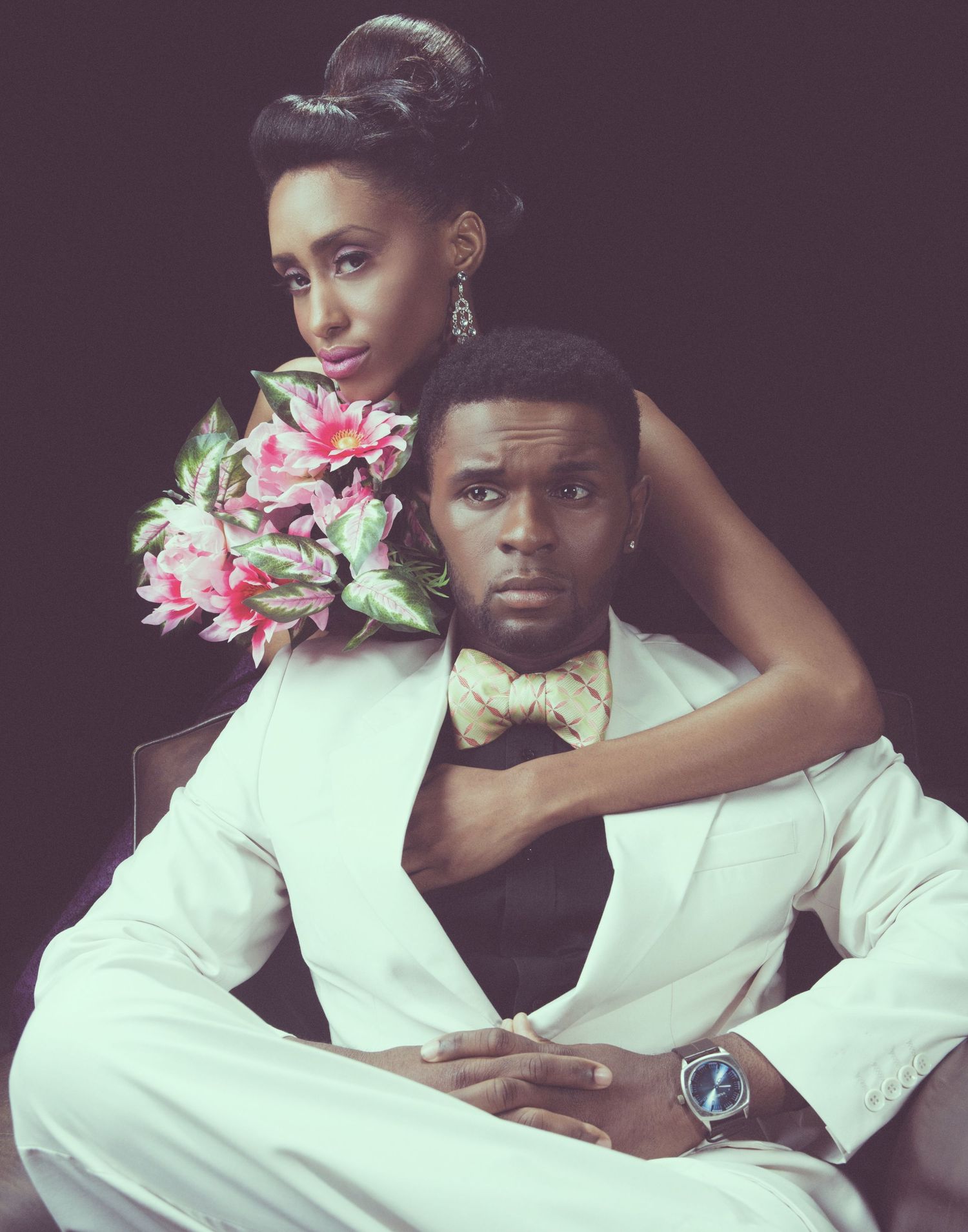 Artistic fashion portrait with pink flowers and white clothing in moody lighting.