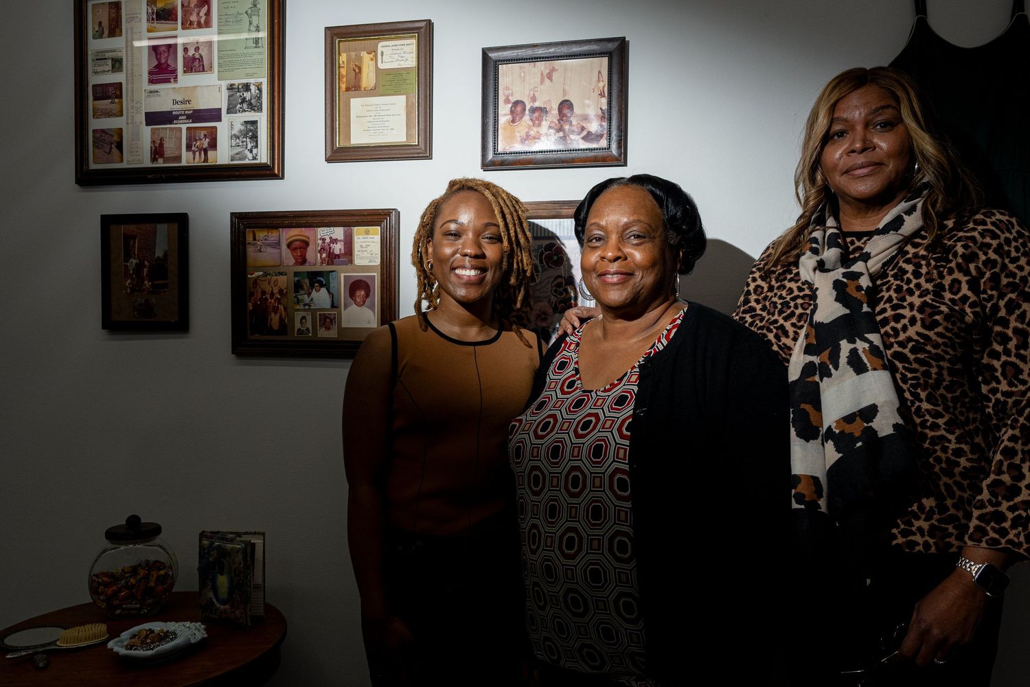 Group of people enjoying a social gathering with framed photos visible on the wall in the background.