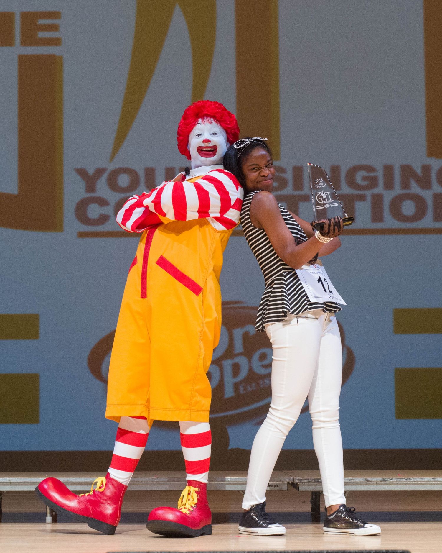 A person in white clothing interacts with the McDonald's mascot Ronald McDonald in a series of playful poses.