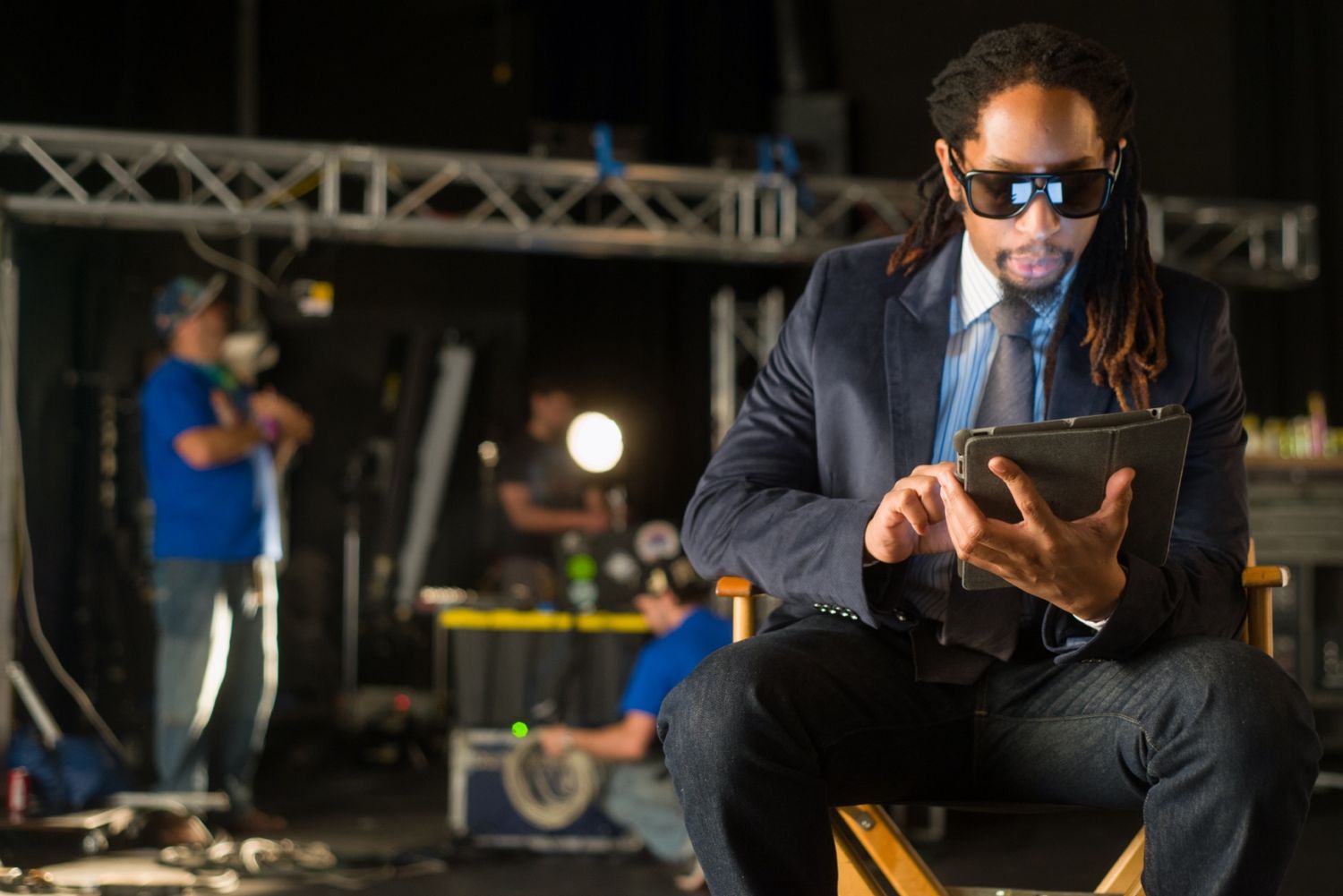 Back stage scene portrait of person holding a device with stage lighting and technical equipment.