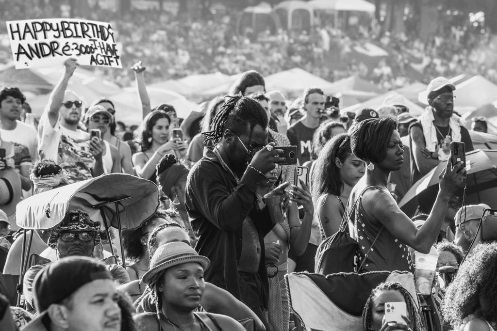 Large crowd of festival goers gather in black and white photograph holding signs during music festival.