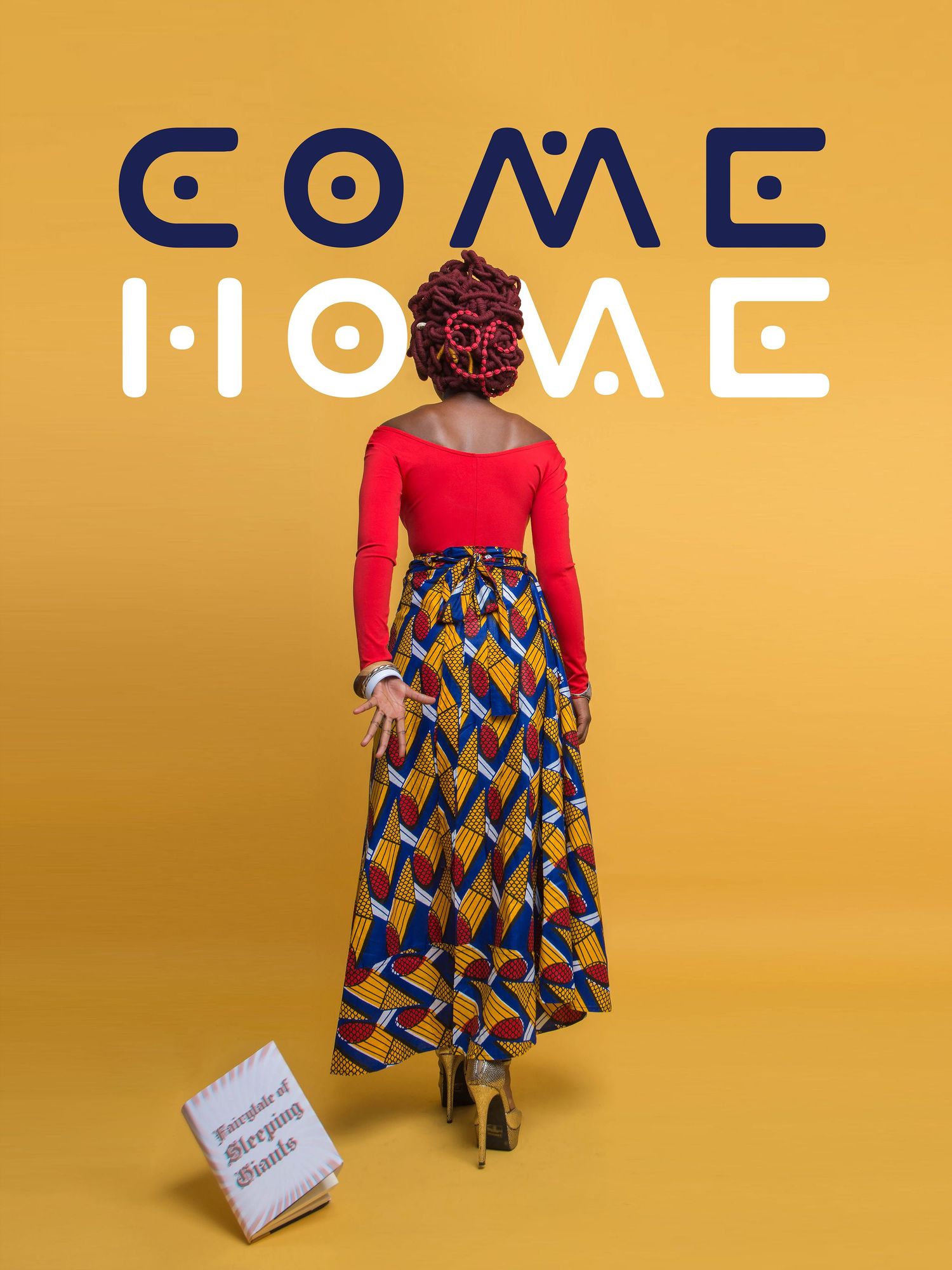 Person in red top and patterned skirt stands against yellow wall with text.