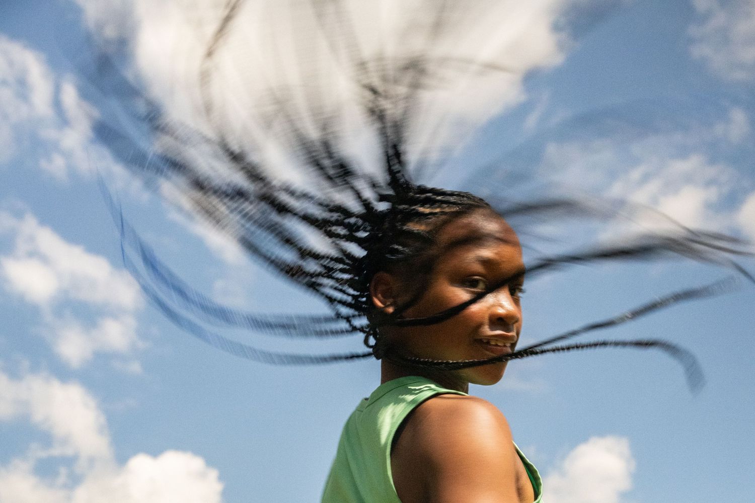 Hair flowing dramatically in the wind against a blue sky background.