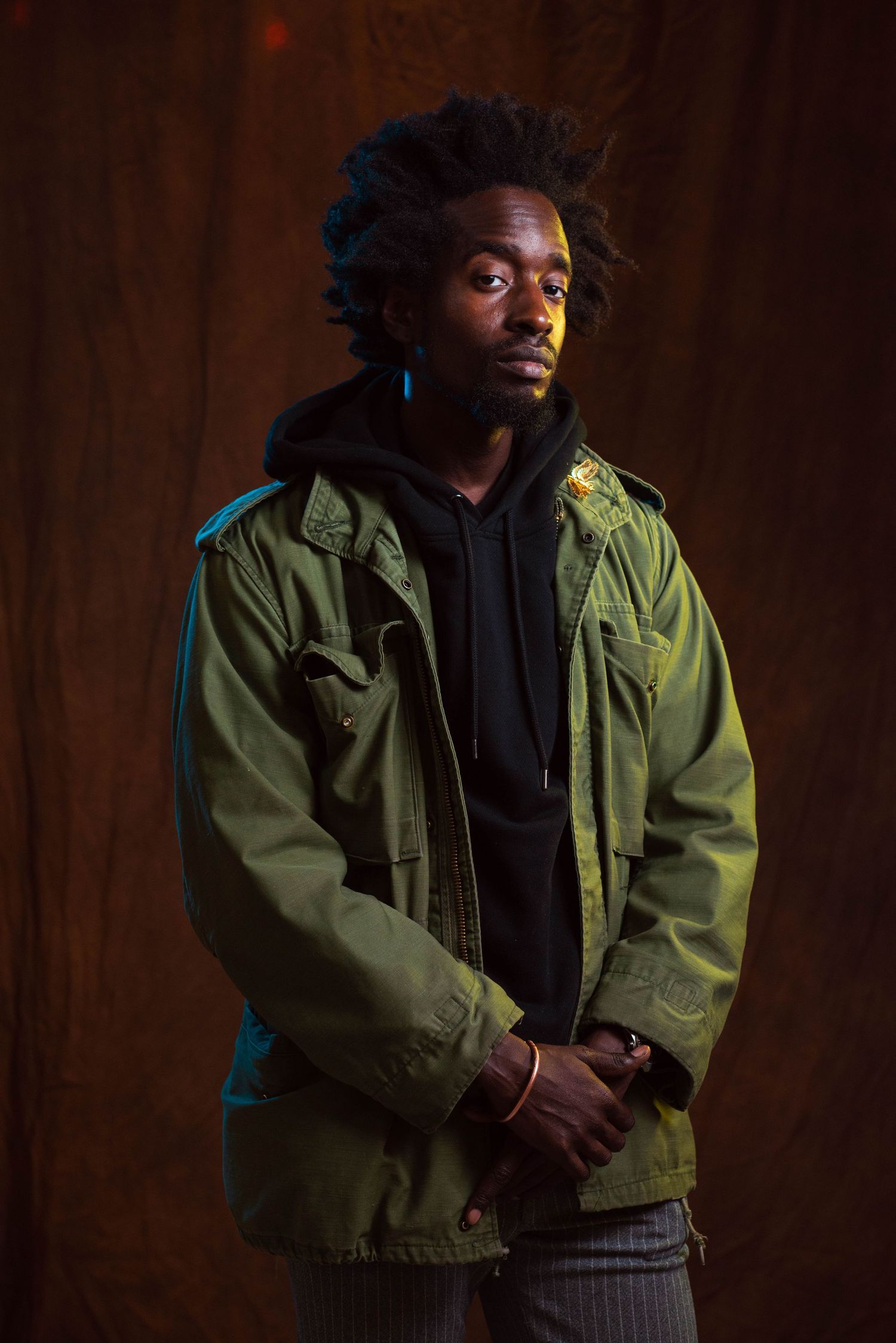 A dramatic portrait series showing someone in a green military jacket and black shirt against a dark background.