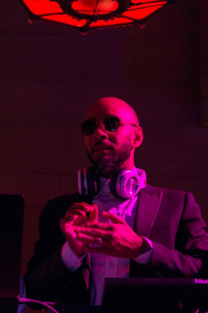 Performer in red and purple lighting holds a microphone during a dramatic stage performance.