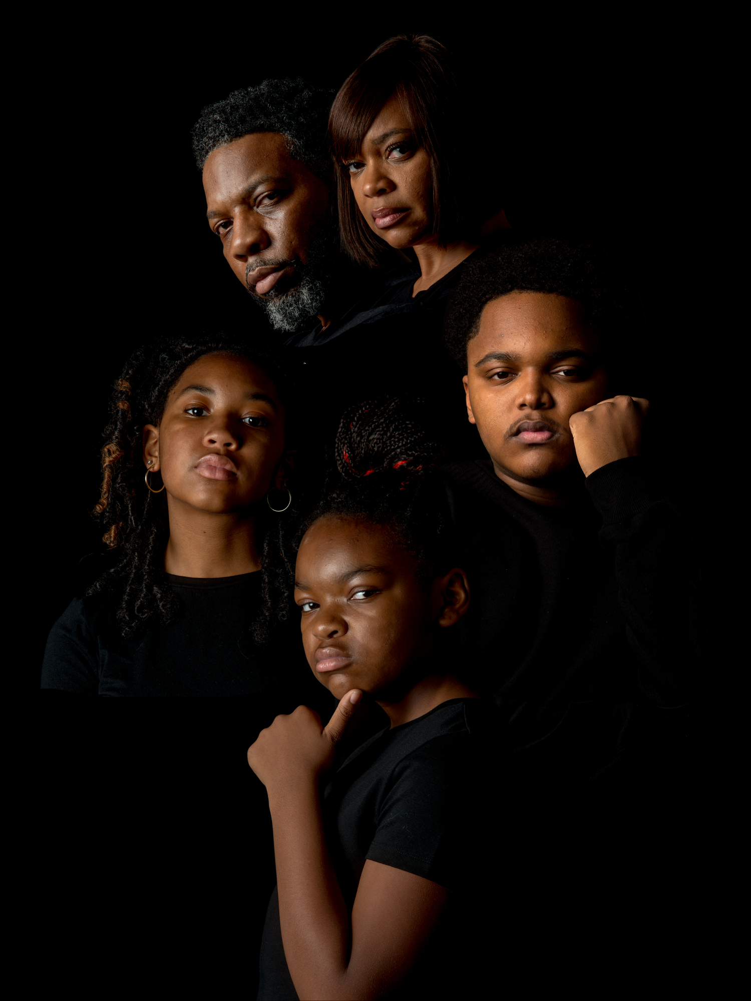 Artistic portrait series featuring a family with black clothing against dark background.