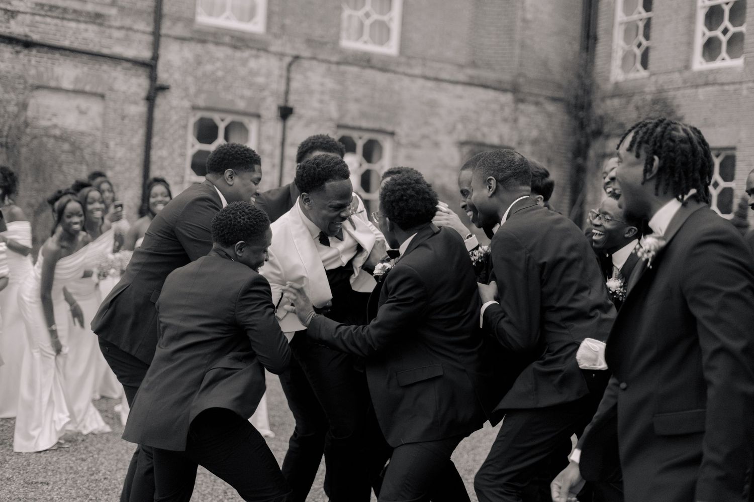 black and white picture of groom picked up by his boys to celebrate him on his wedding day