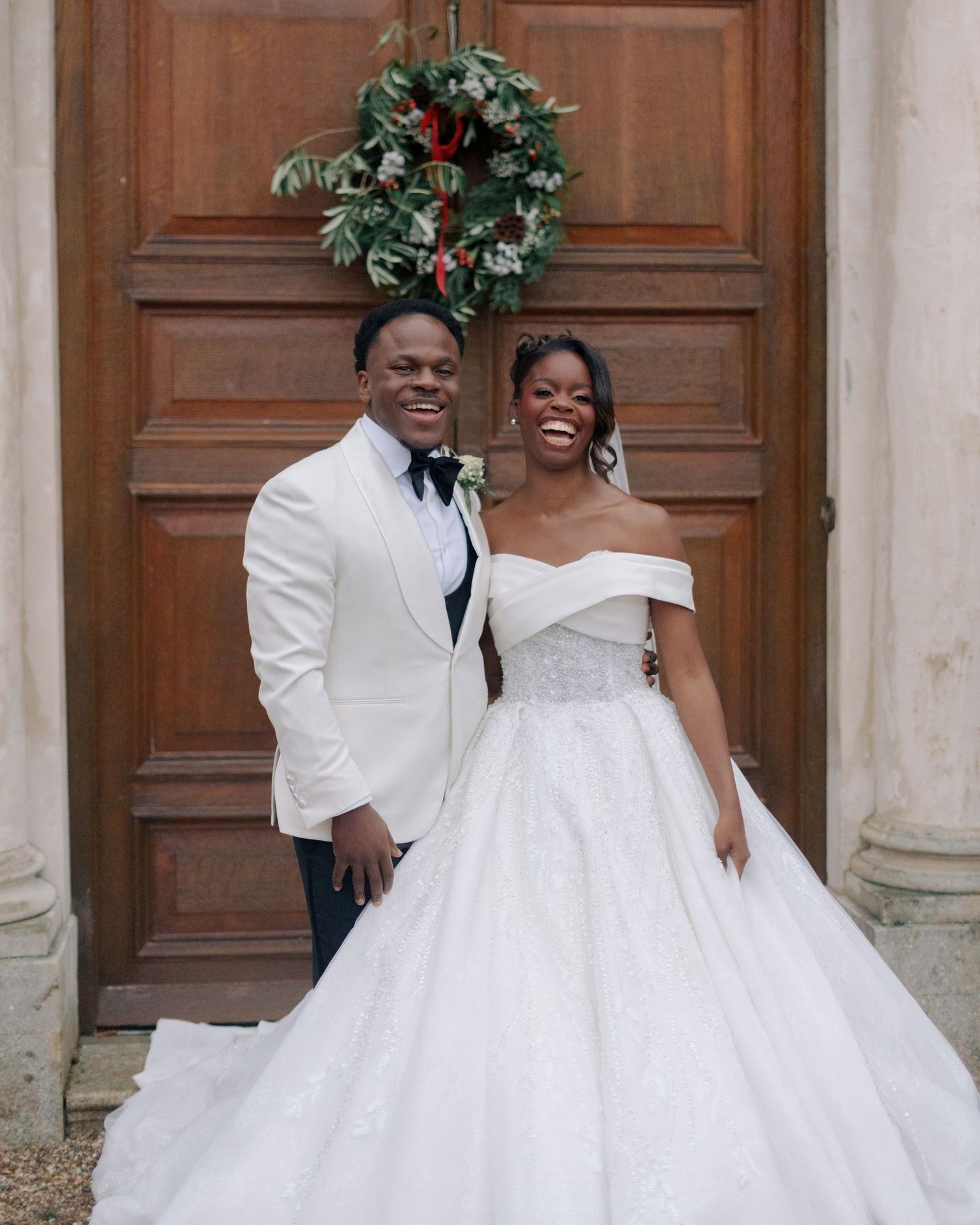 couple posing in front of brown door at braxted park estate