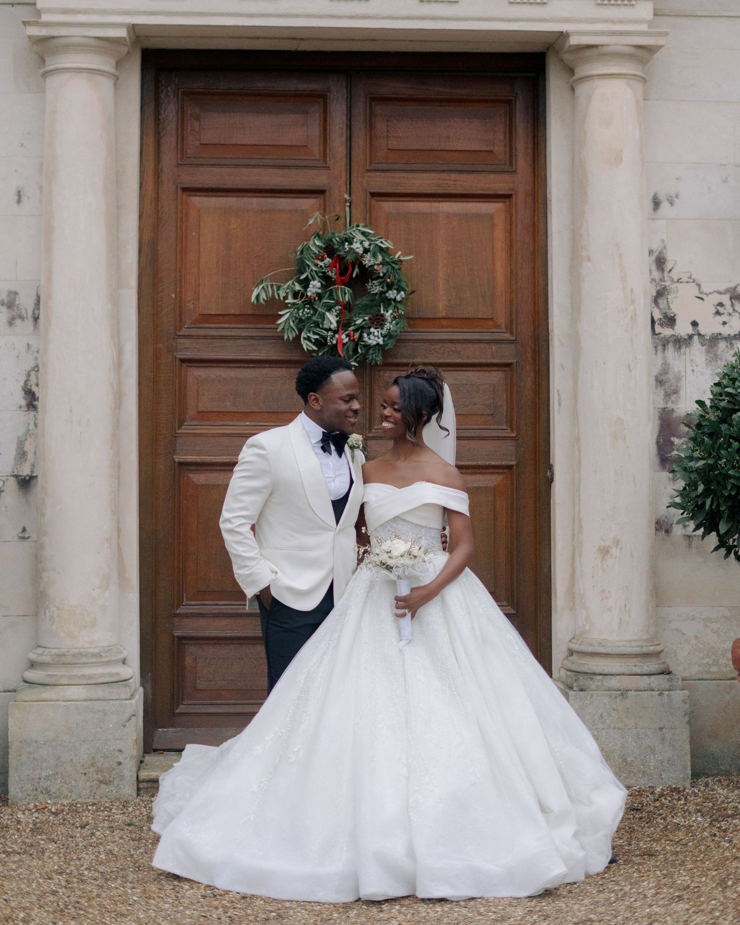 bride and groom posing in front of big brown door at braxted park