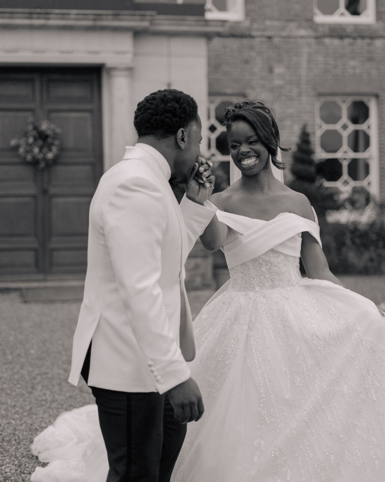 black and white picture of groom kissing bride hand