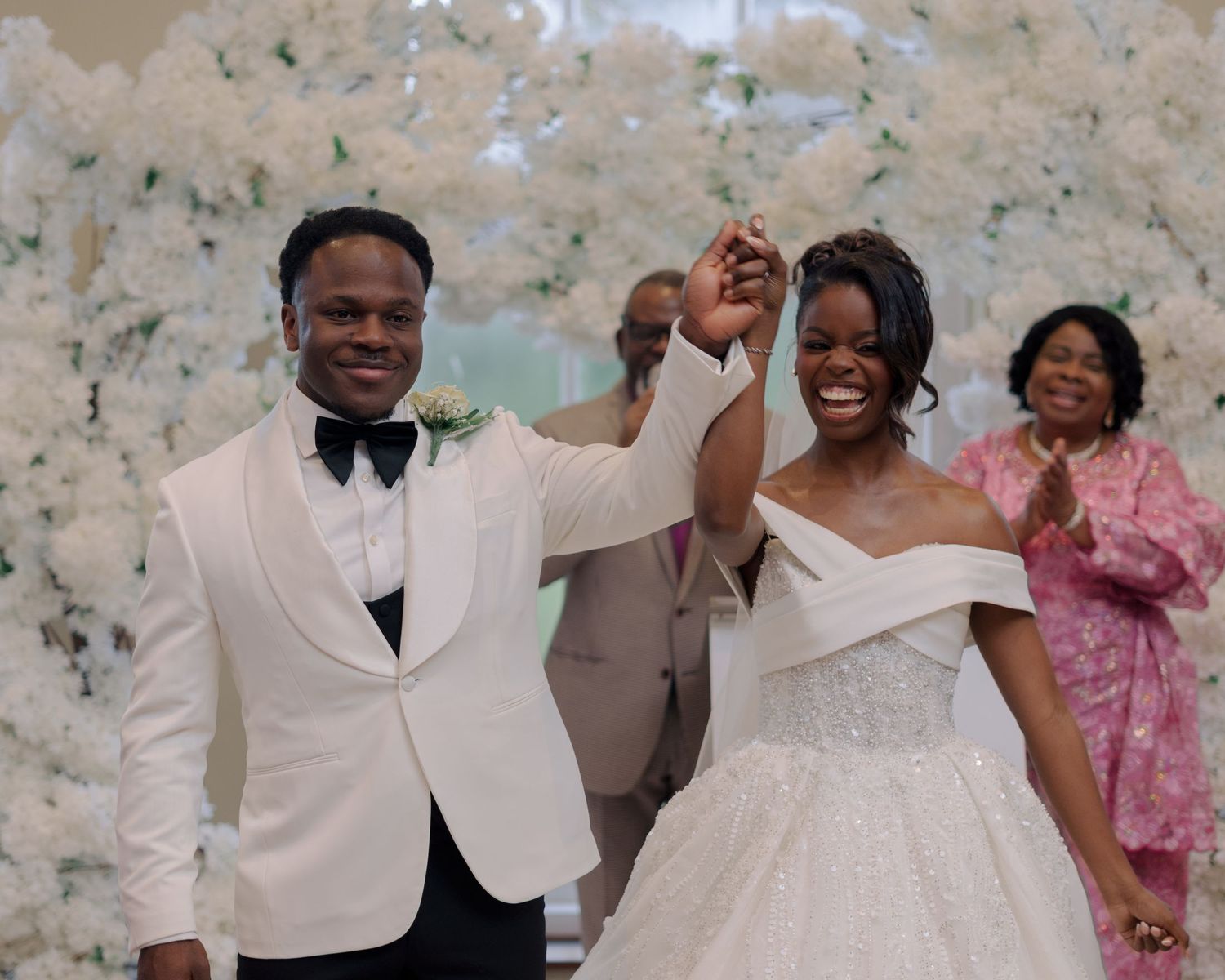 groom showing off his bride as he lifts her hand after they're declared husband and wife while standing in the aisle.