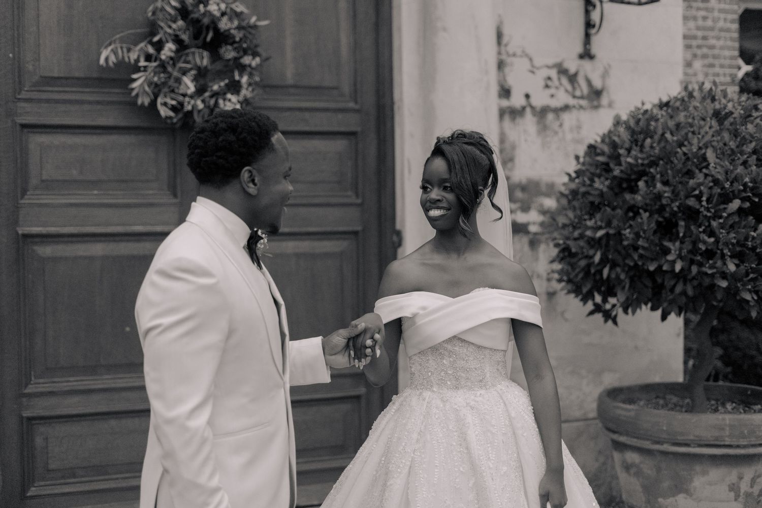 black and white of bride and groom walking hand in hand while smiling