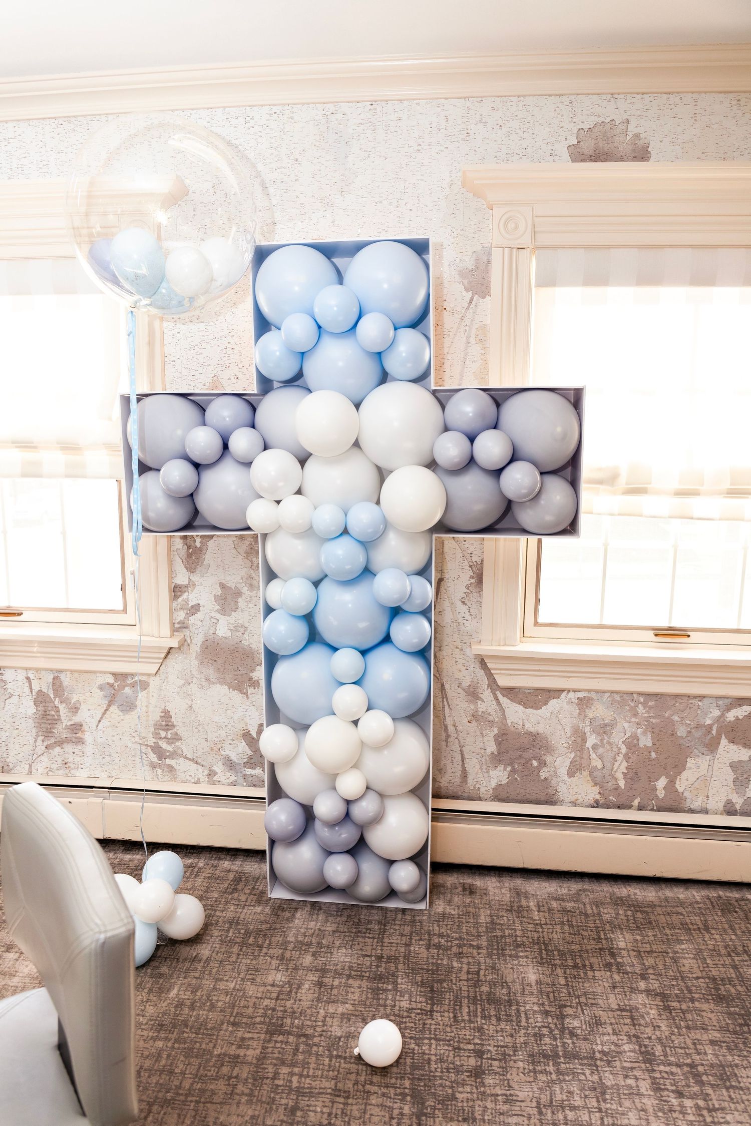 Balloon wall installation in progress showing blue and white balloons arranged in sections against a white interior wall.