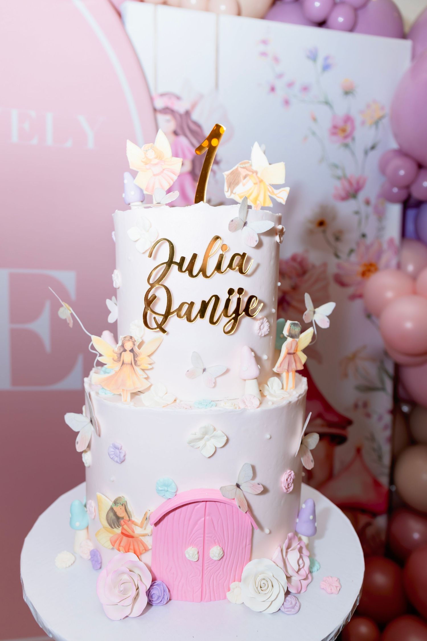 White wedding cake decorated with delicate pink and purple butterflies and floral accents on a pink background.