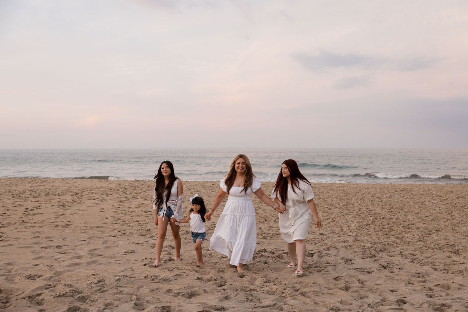 A mom and her daughter's walking on the beach at sunset.