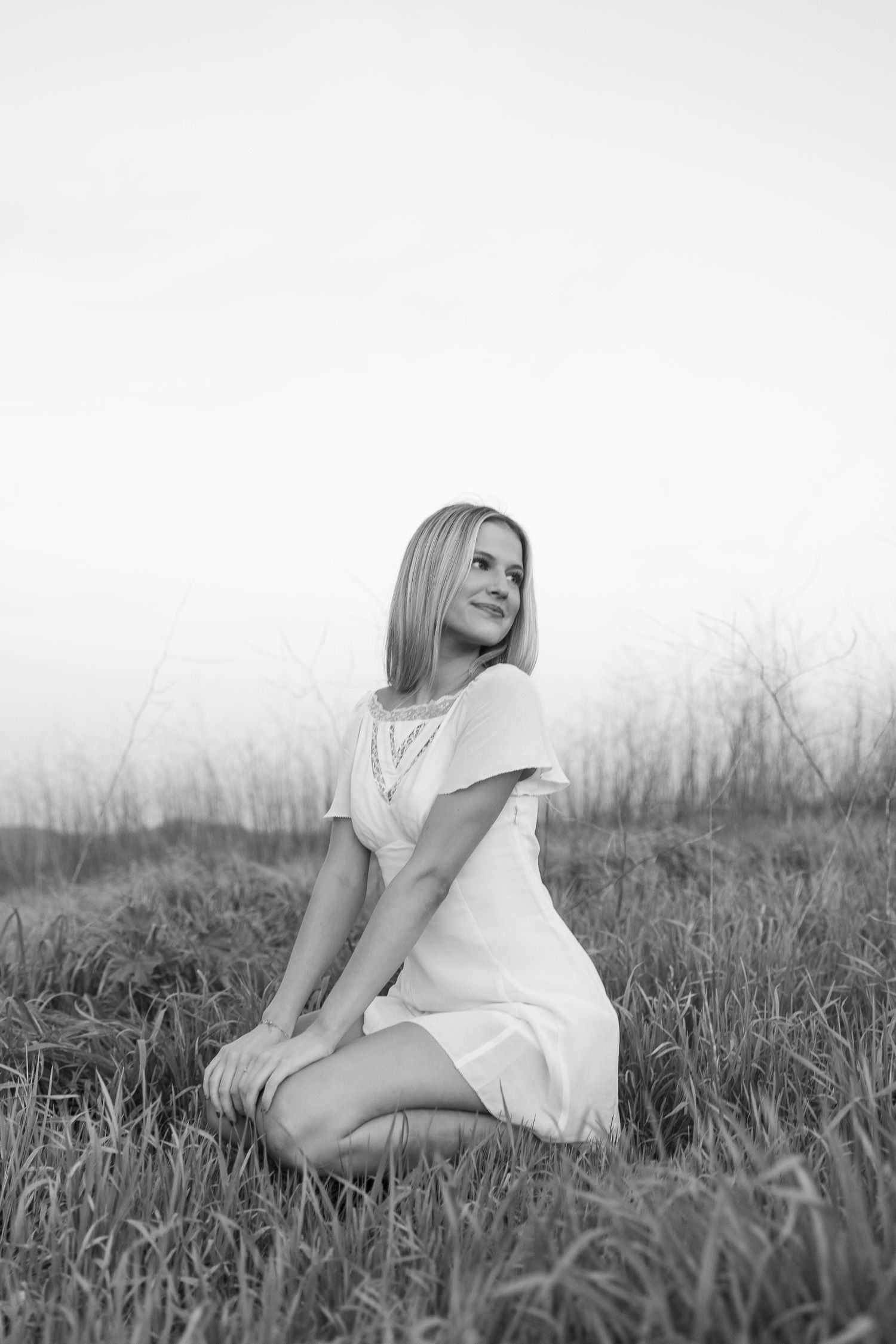 Black and white artistic portrait series showing relaxed poses in a grassy field.