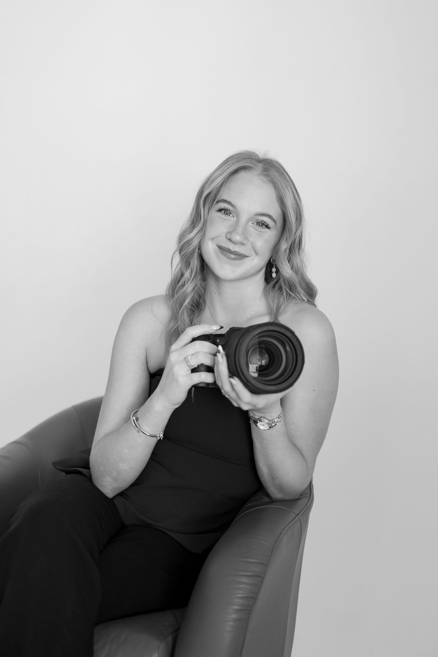 Professional photographer poses with camera in black and white studio portraits.