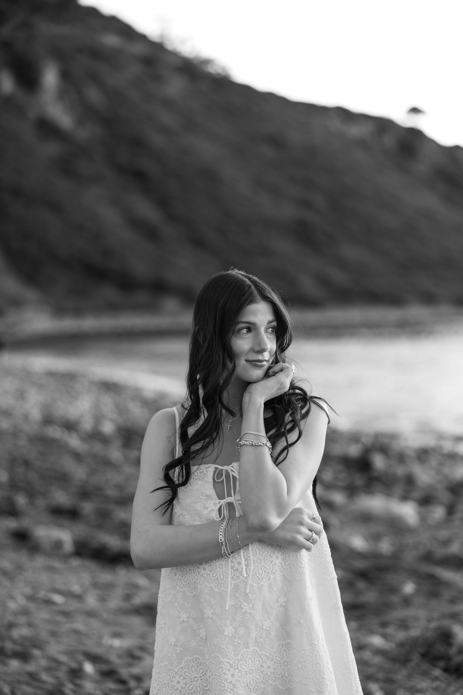 A black and white portrait of someone in a sparkly dress by the ocean.