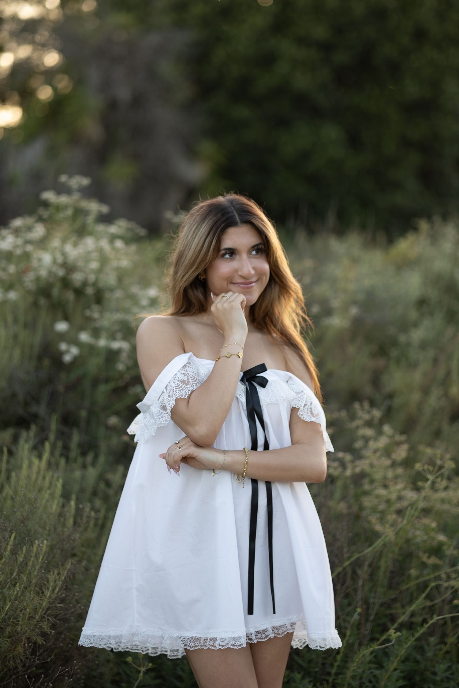 Artistic portrait in white lace dress amid natural foliage.