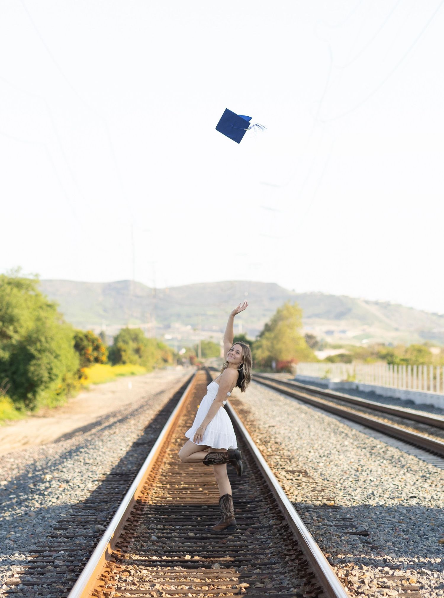 A series of photos showing someone lying between train tracks in a white dress against a mountain backdrop.