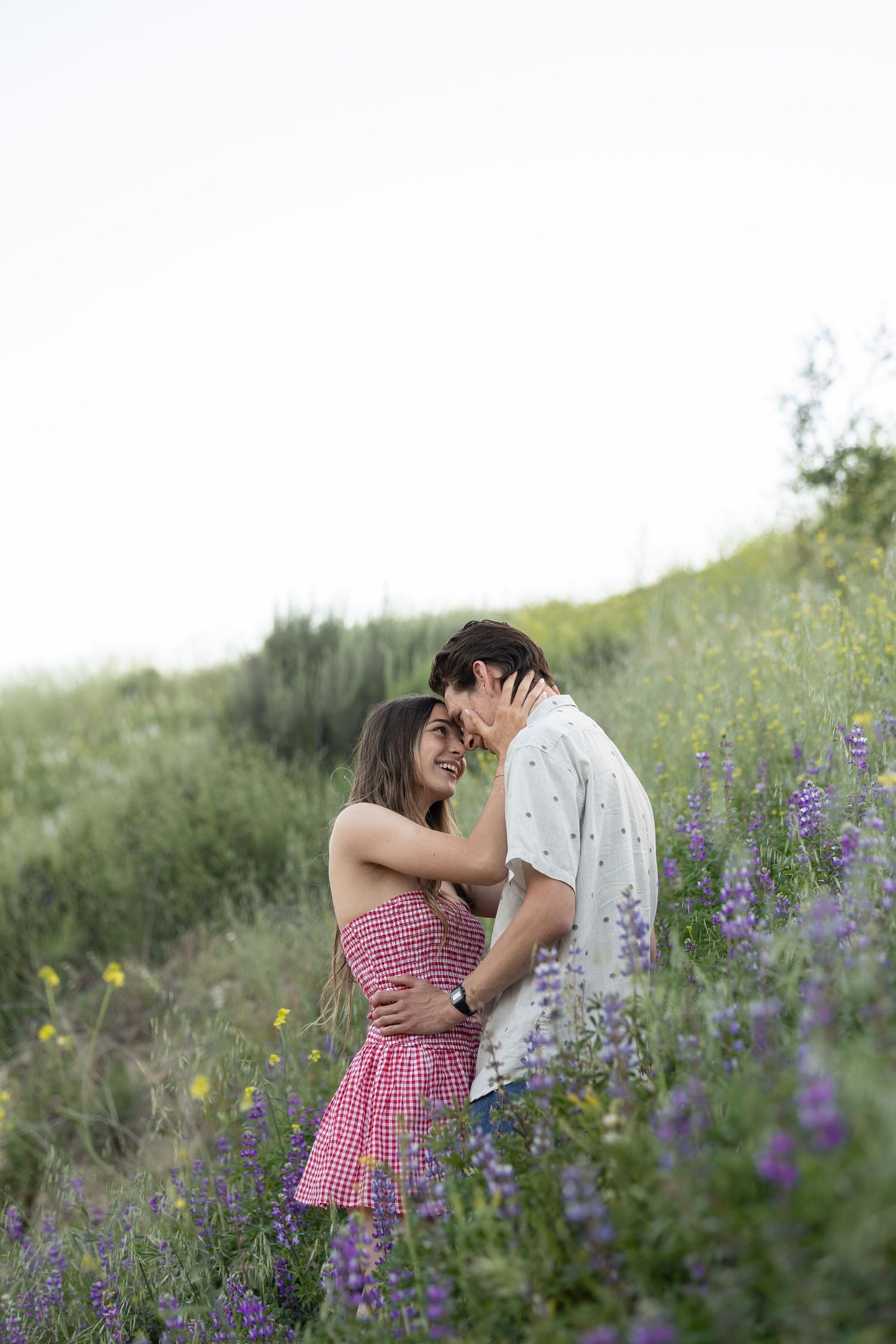 A romantic moment among purple wildflowers on a hillside at dusk.