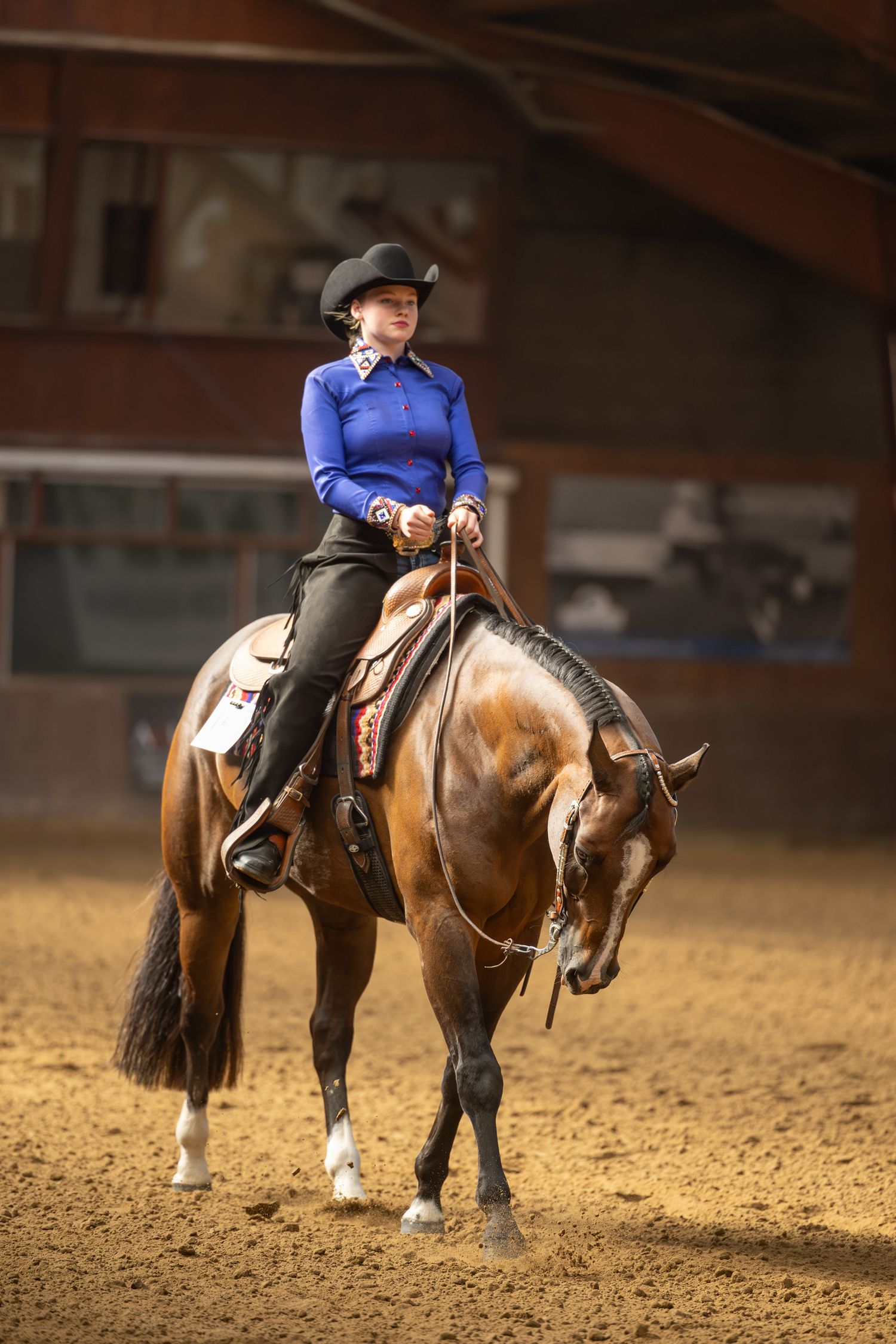 Riders practicing horsemanship in an indoor arena with sandy footing.