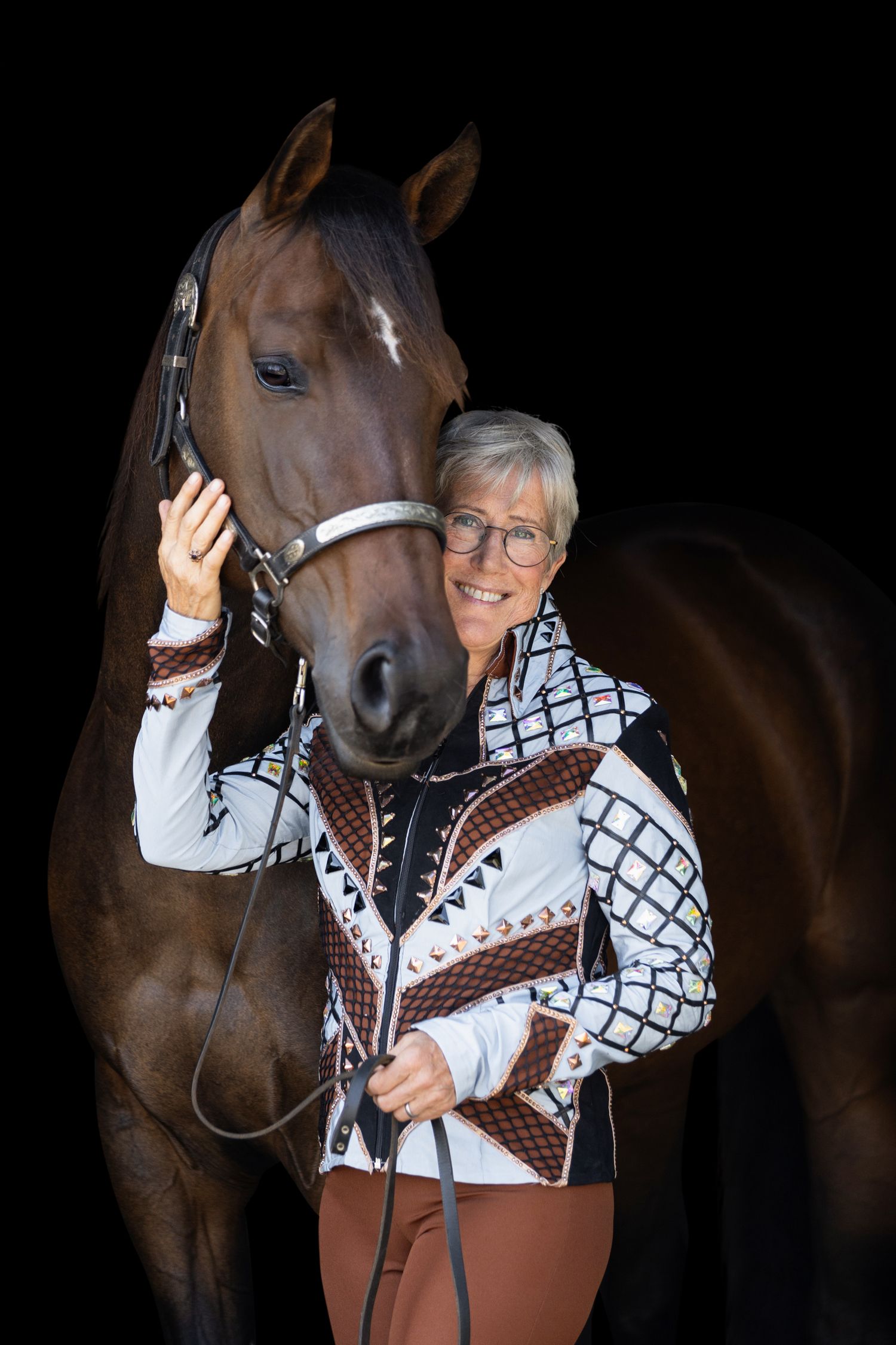 A brown horse and handler share an intimate moment against a dark background.