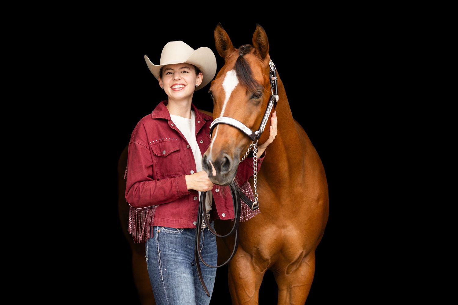 Horse and western rider posing together against black background in studio setting.