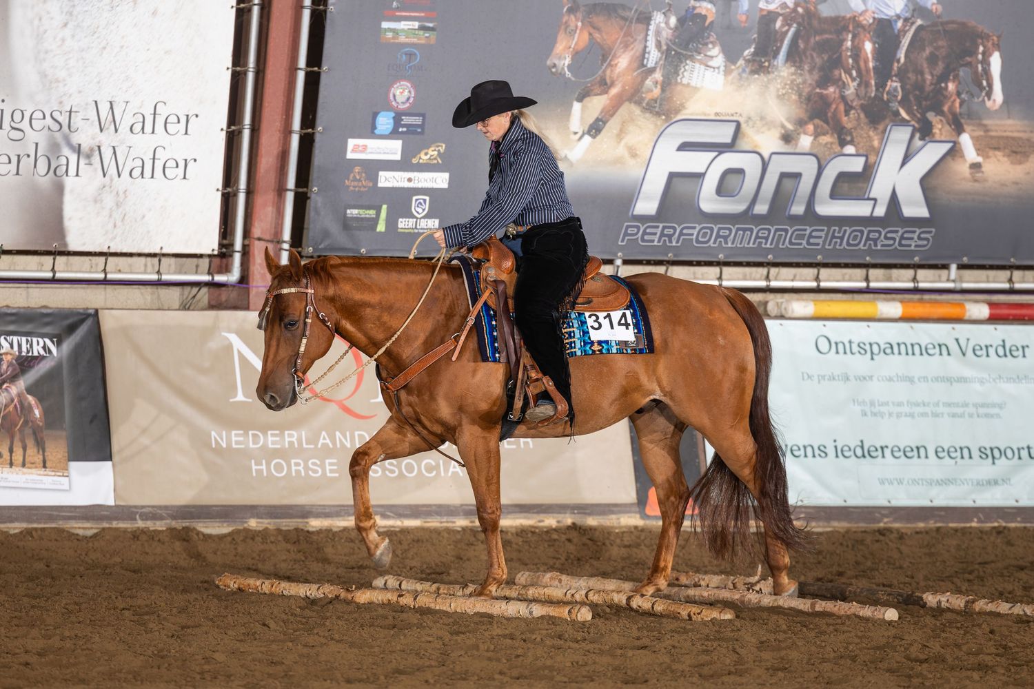 Rider in black hat on chestnut horse competing in western equestrian event at Fonck arena with number 314.