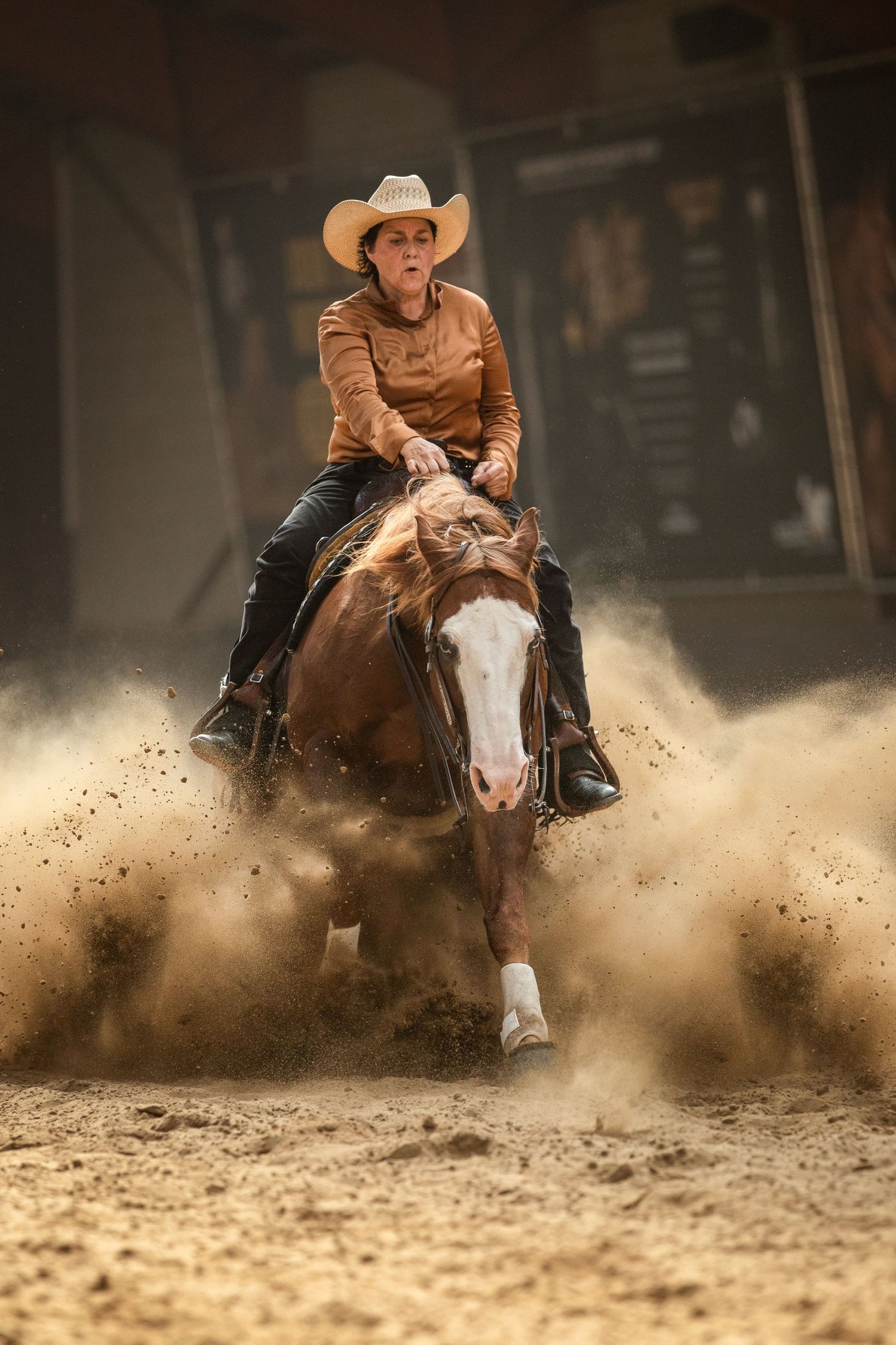 A horse and rider kick up dust during an intense western riding performance.