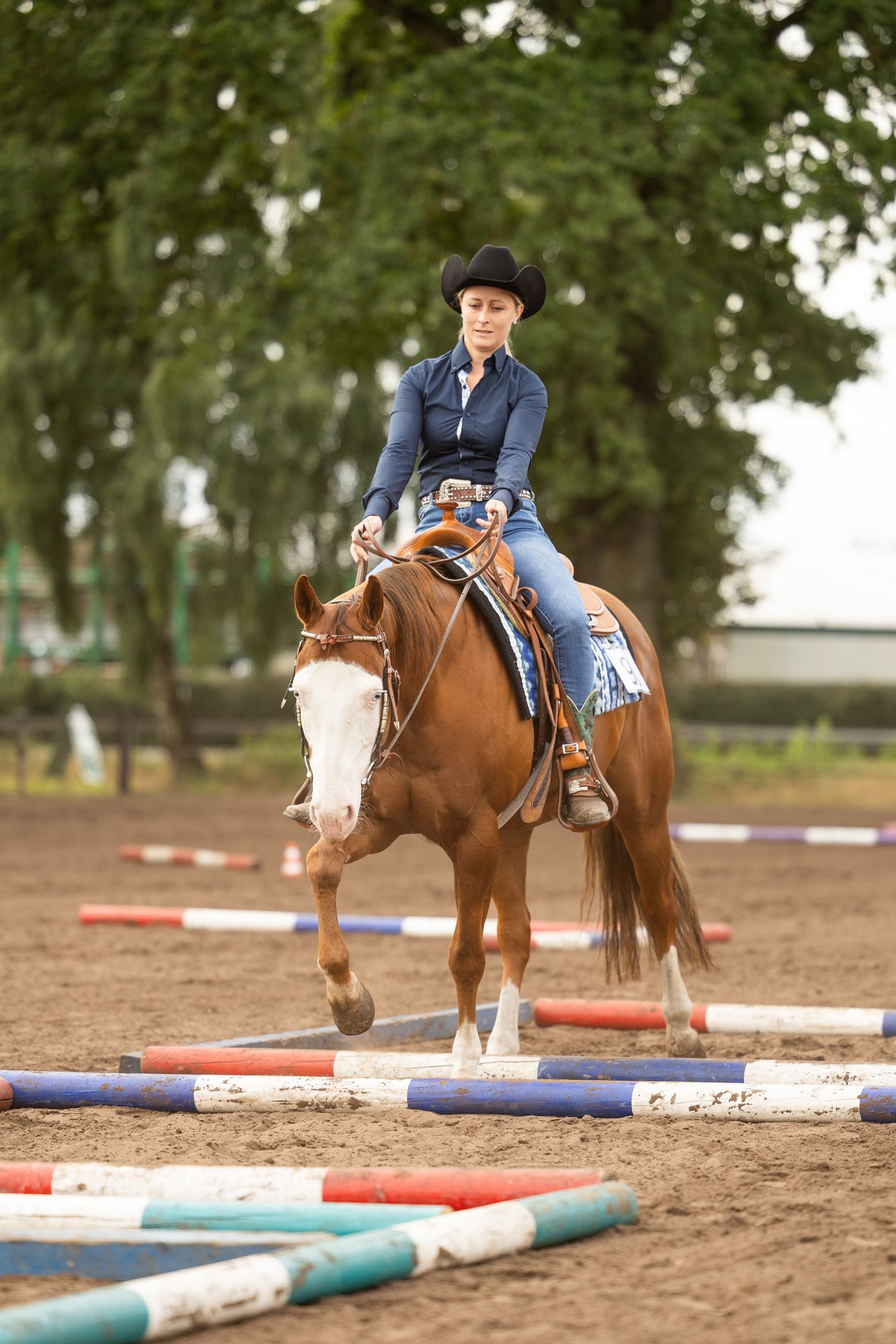 A paint horse navigates through poles during a western riding competition.