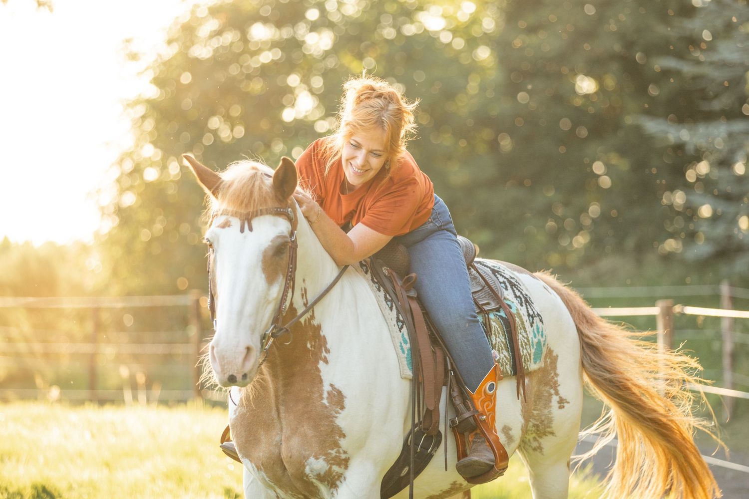 Paint horse and rider enjoying sunset ride in grassy field.