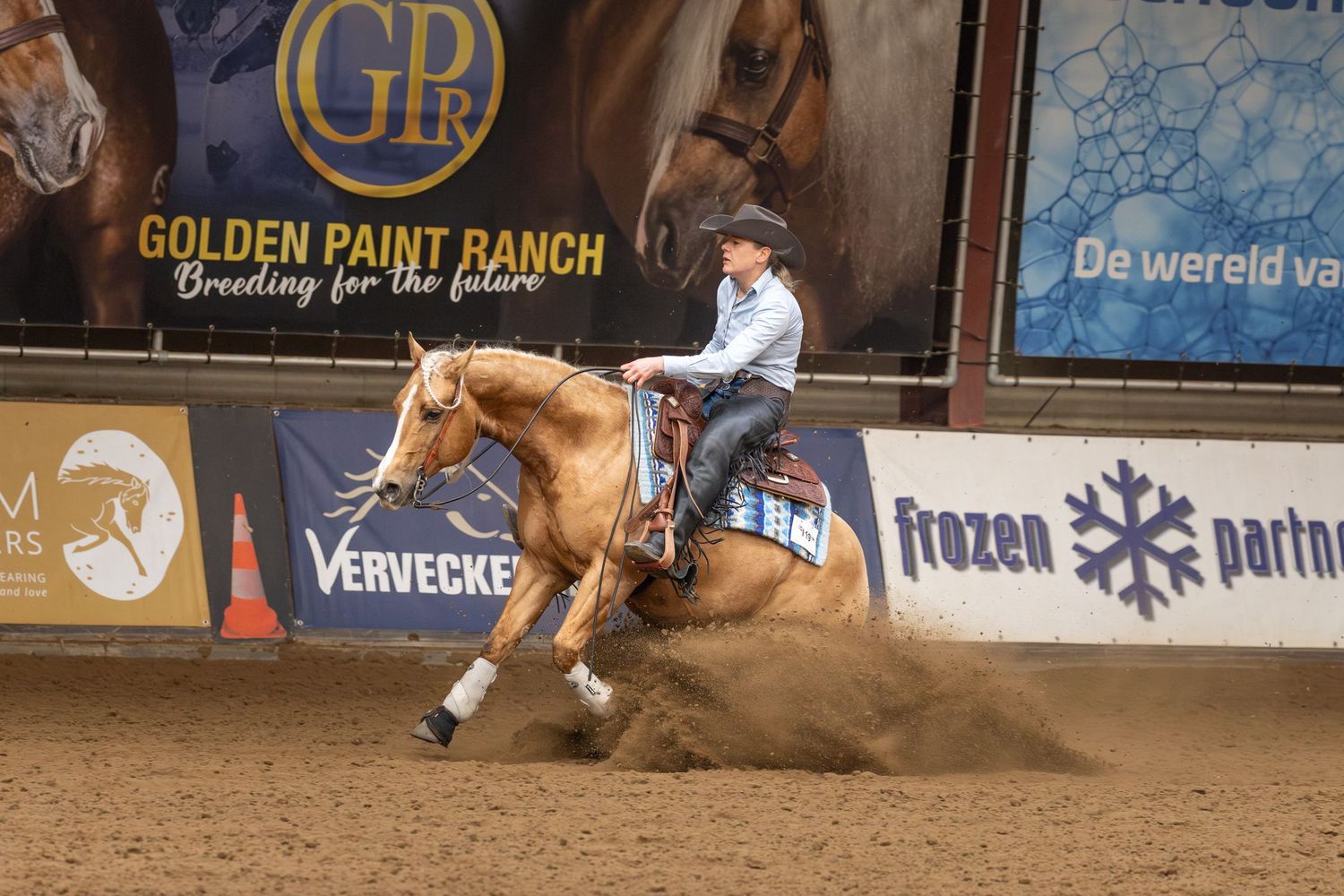 A rider competes in a rodeo event, guiding their horse through a barrel racing pattern in an indoor arena.