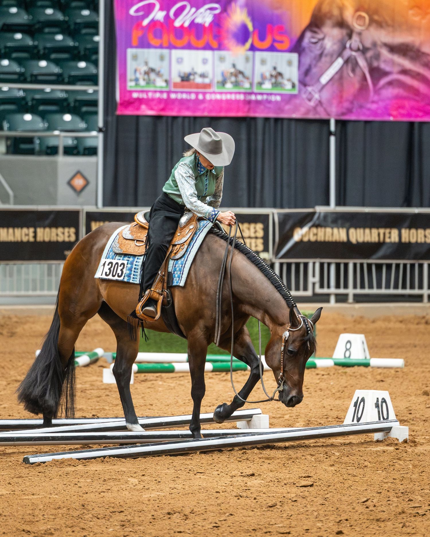 Rider in white hat on bay horse navigating poles at indoor Western equestrian competition.