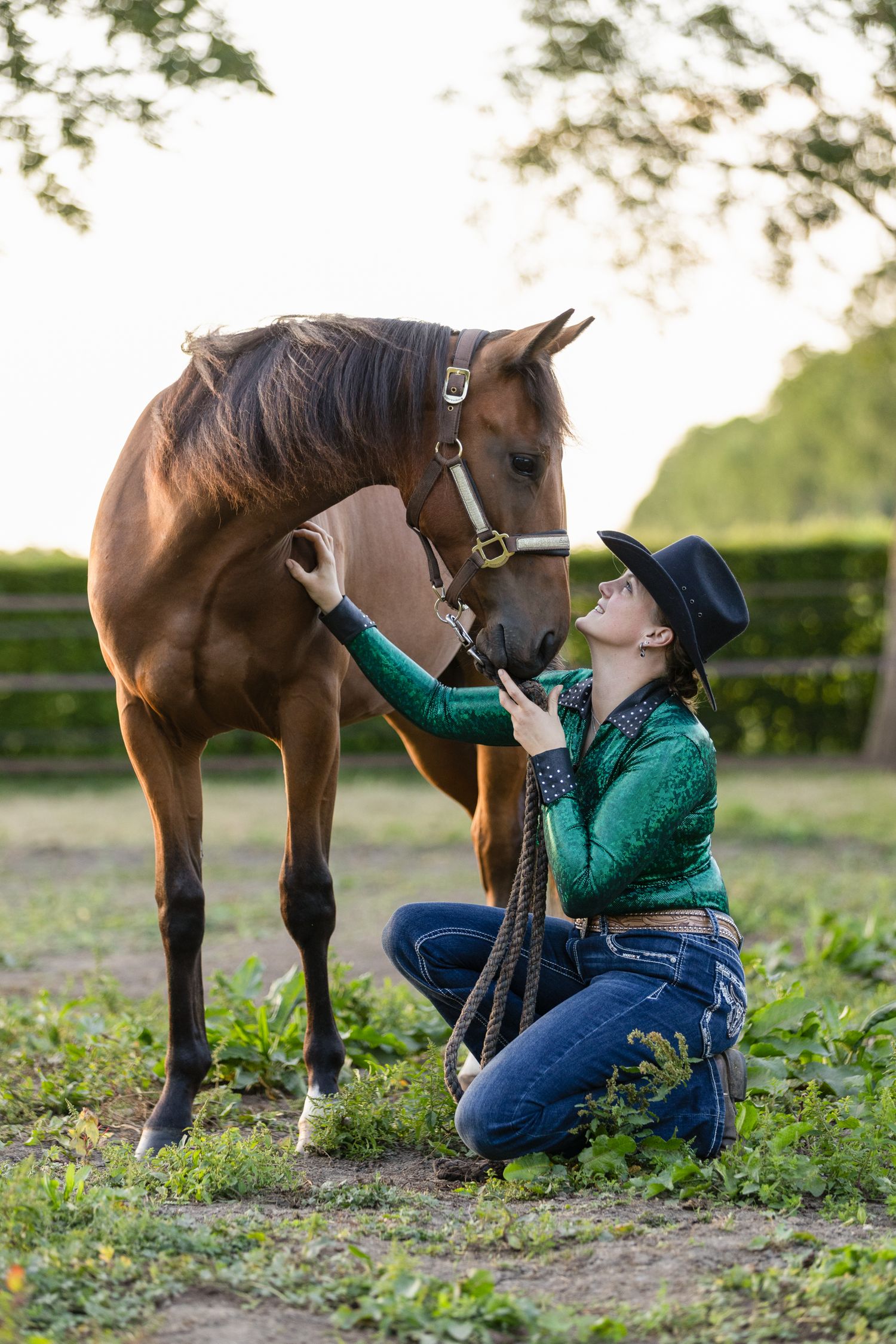 A tender interaction between a horse and handler in a grassy field.