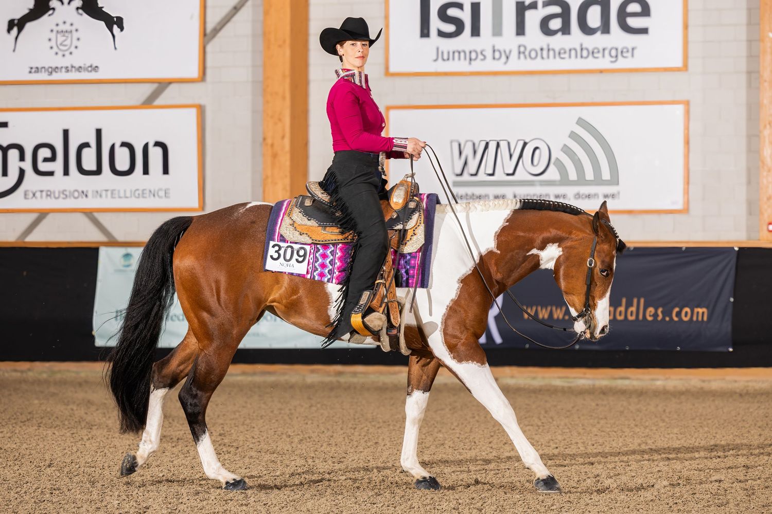 Western riding competition in progress inside an arena with sponsor banners visible.