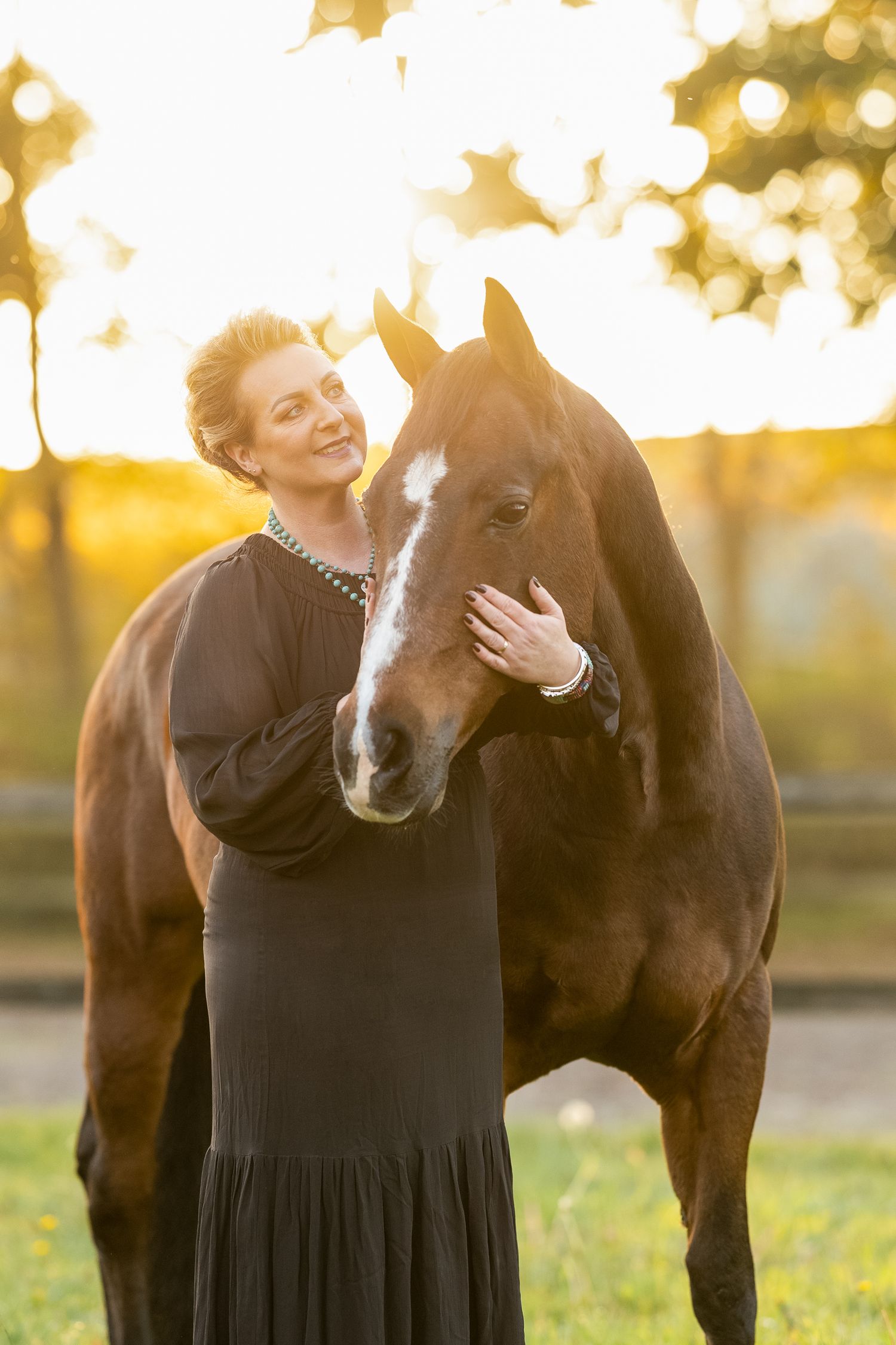 Heartwarming interaction between Quarter horse and person in black dress during sunset photoshoot.