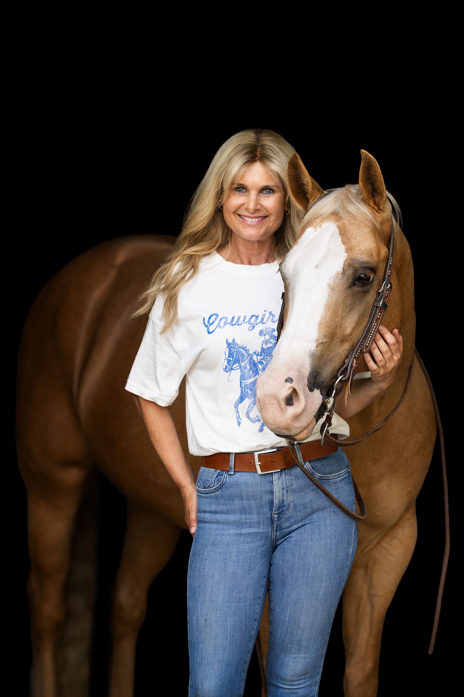 A beautiful chestnut horse poses with its handler against a dark background.