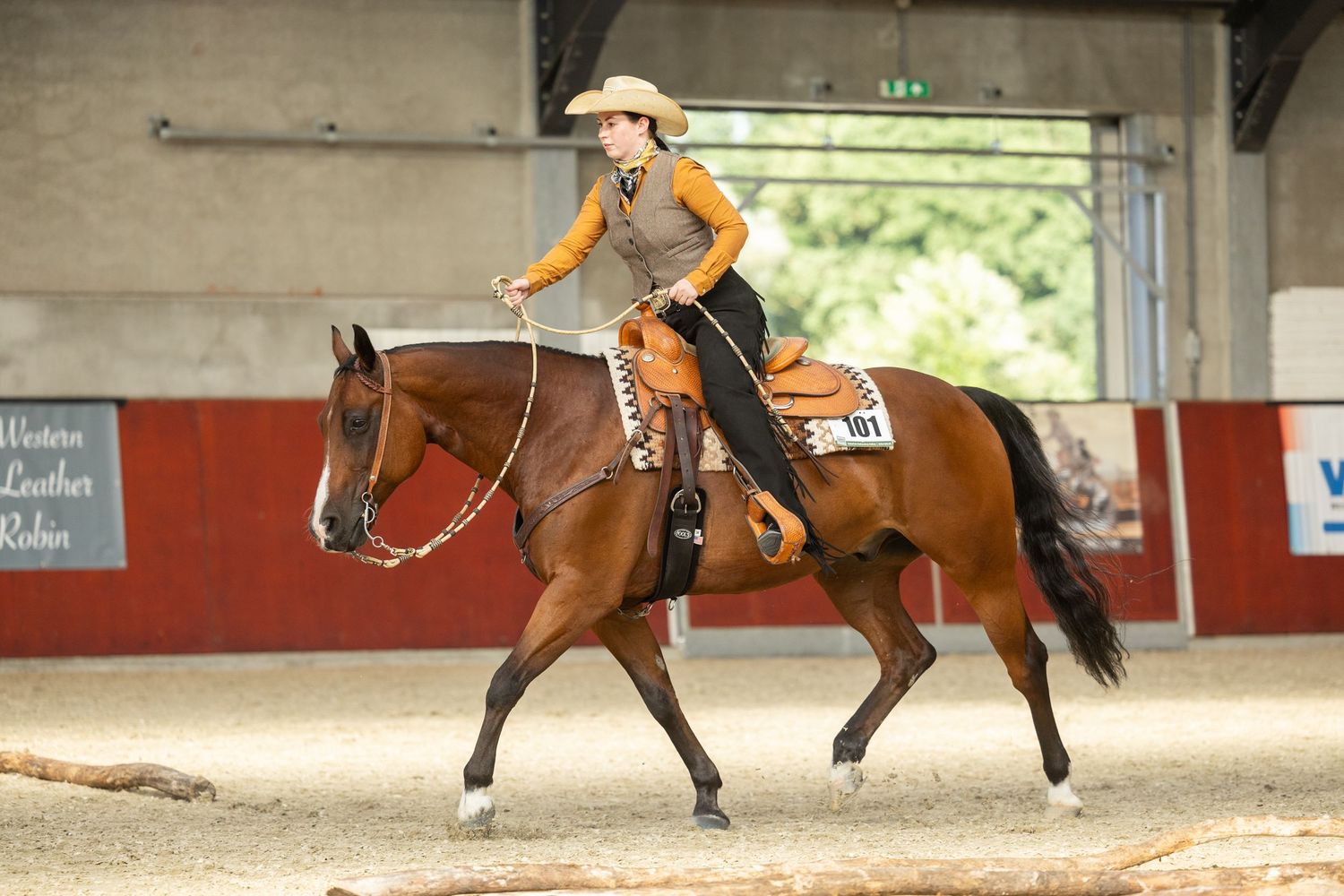 A horse and rider competing in a western riding event in an indoor arena.