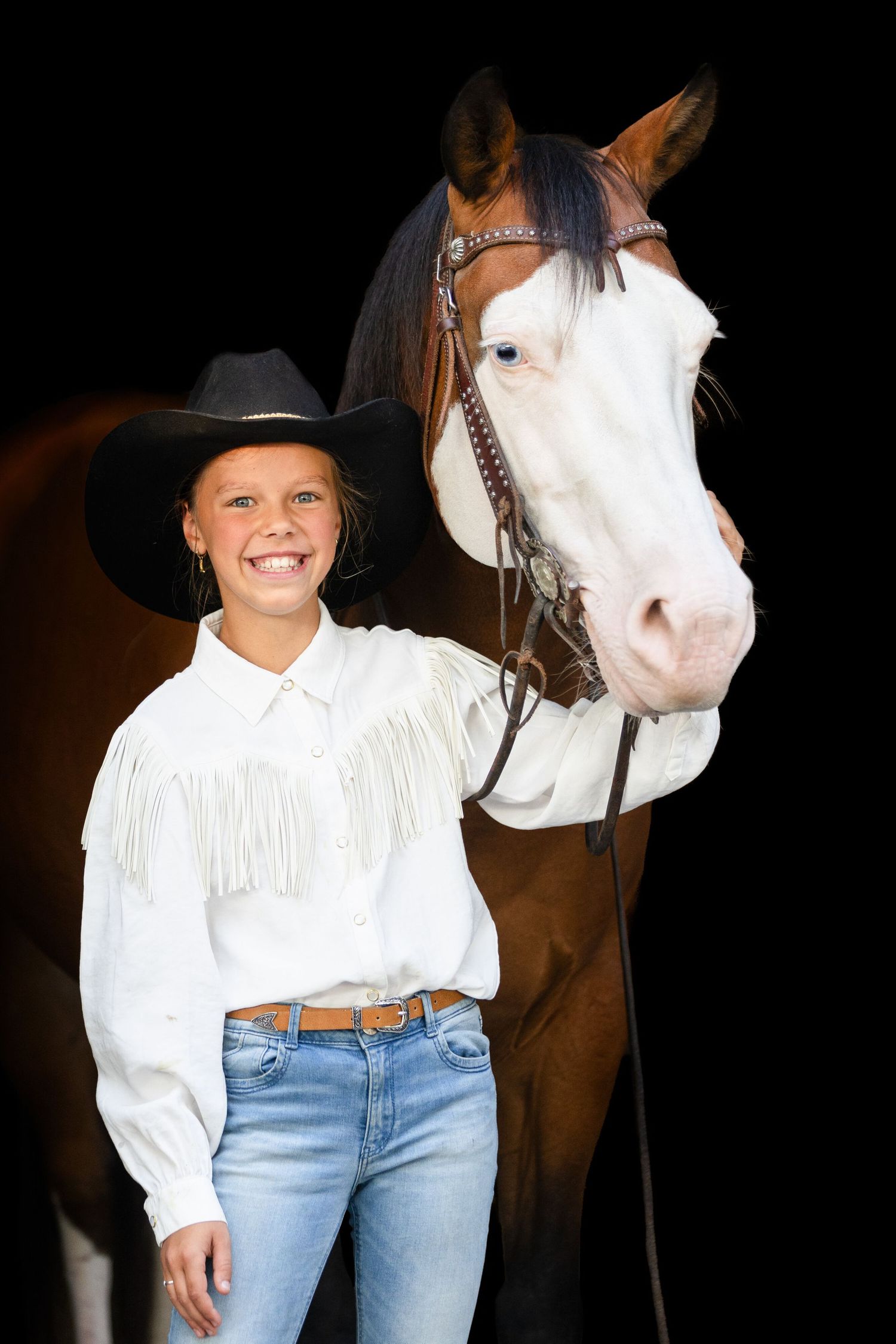A paint horse with distinctive white and brown markings stands against a dark background.