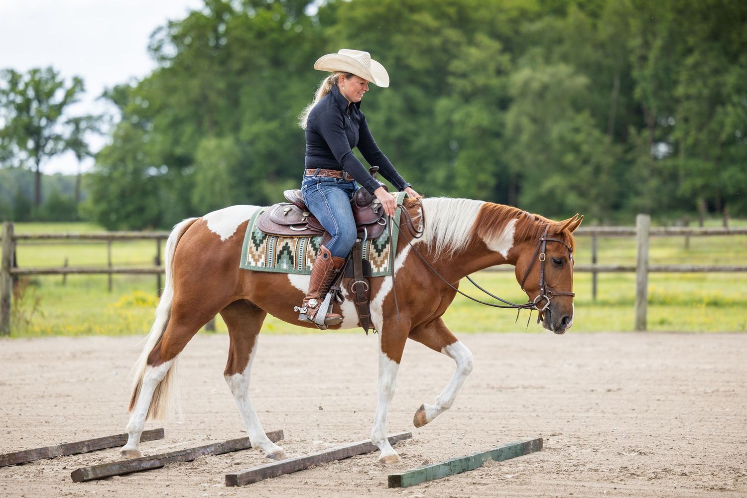 Horse and rider practicing riding techniques in a sandy outdoor arena.