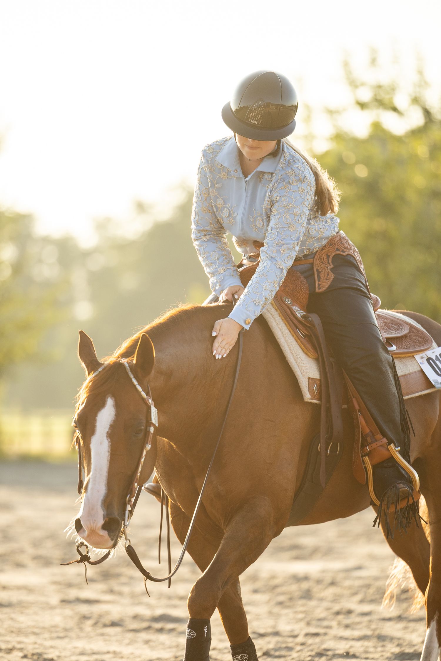 Riders on horseback practicing equestrian skills in a sunlit outdoor arena.