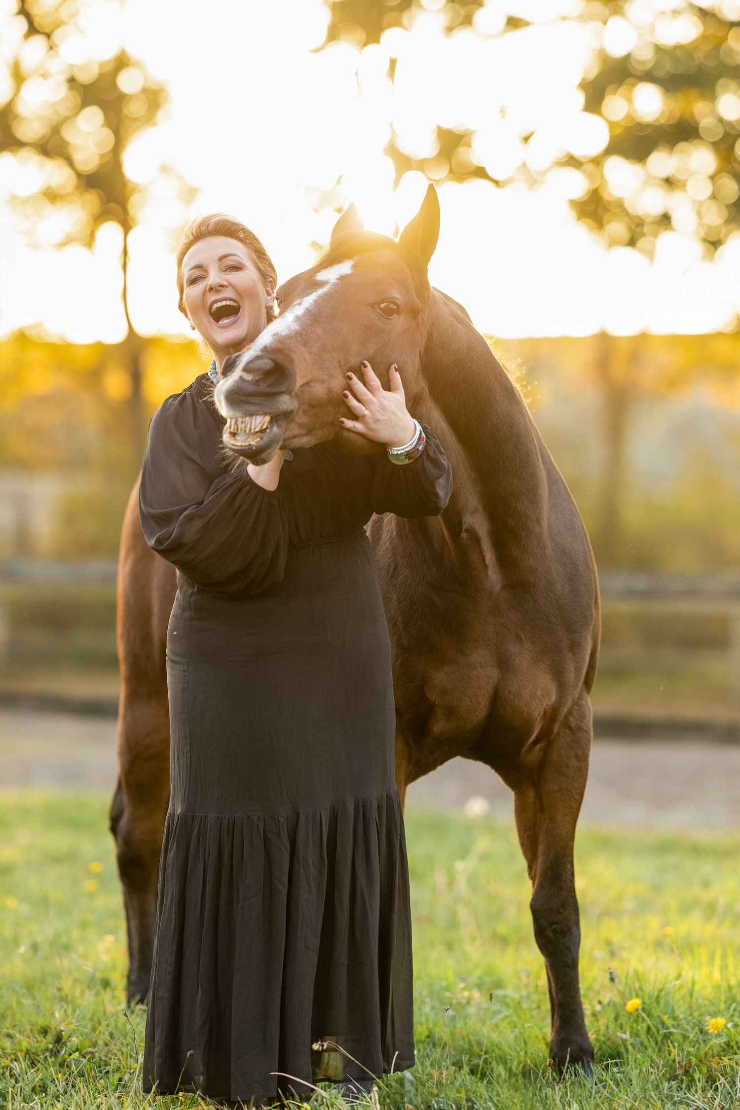 Joyful interaction between Quarterhorse and person in black dress captured during golden hour.