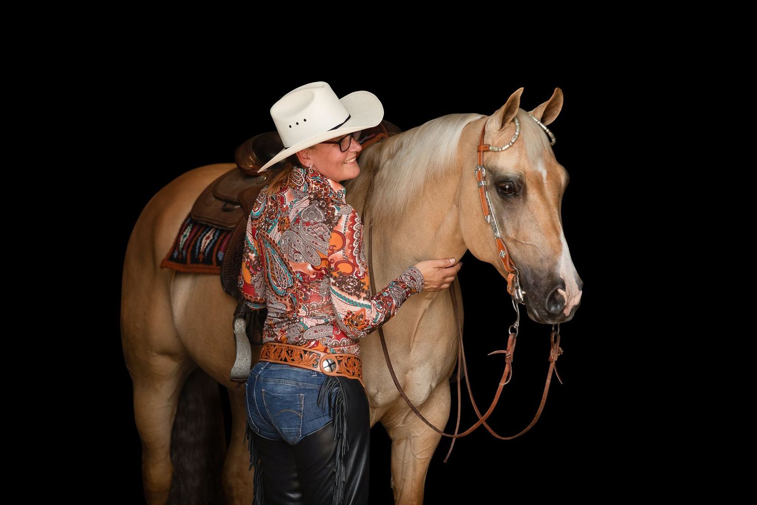 Western-style horses lined up at a show or competition against dark background.