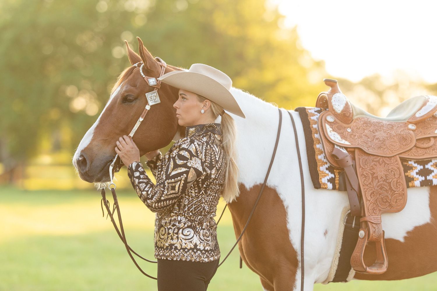 Western style equestrian photo session with horse in golden sunlit field.