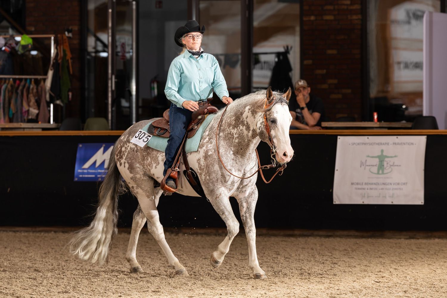 White horse performing a reining pattern with rider in western attire.