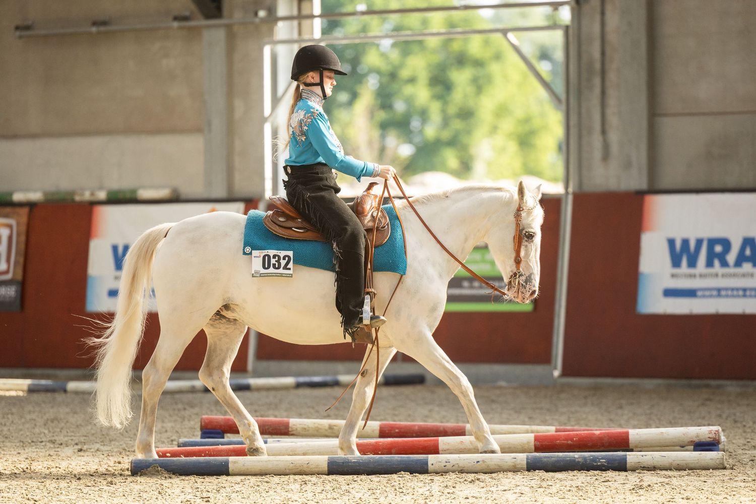 White horse and rider navigating poles in western riding competition.