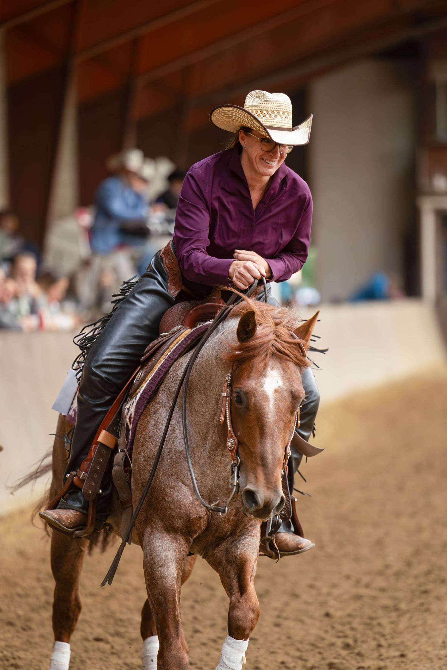 Western rider guiding horse through reining patterns in indoor arena setting.